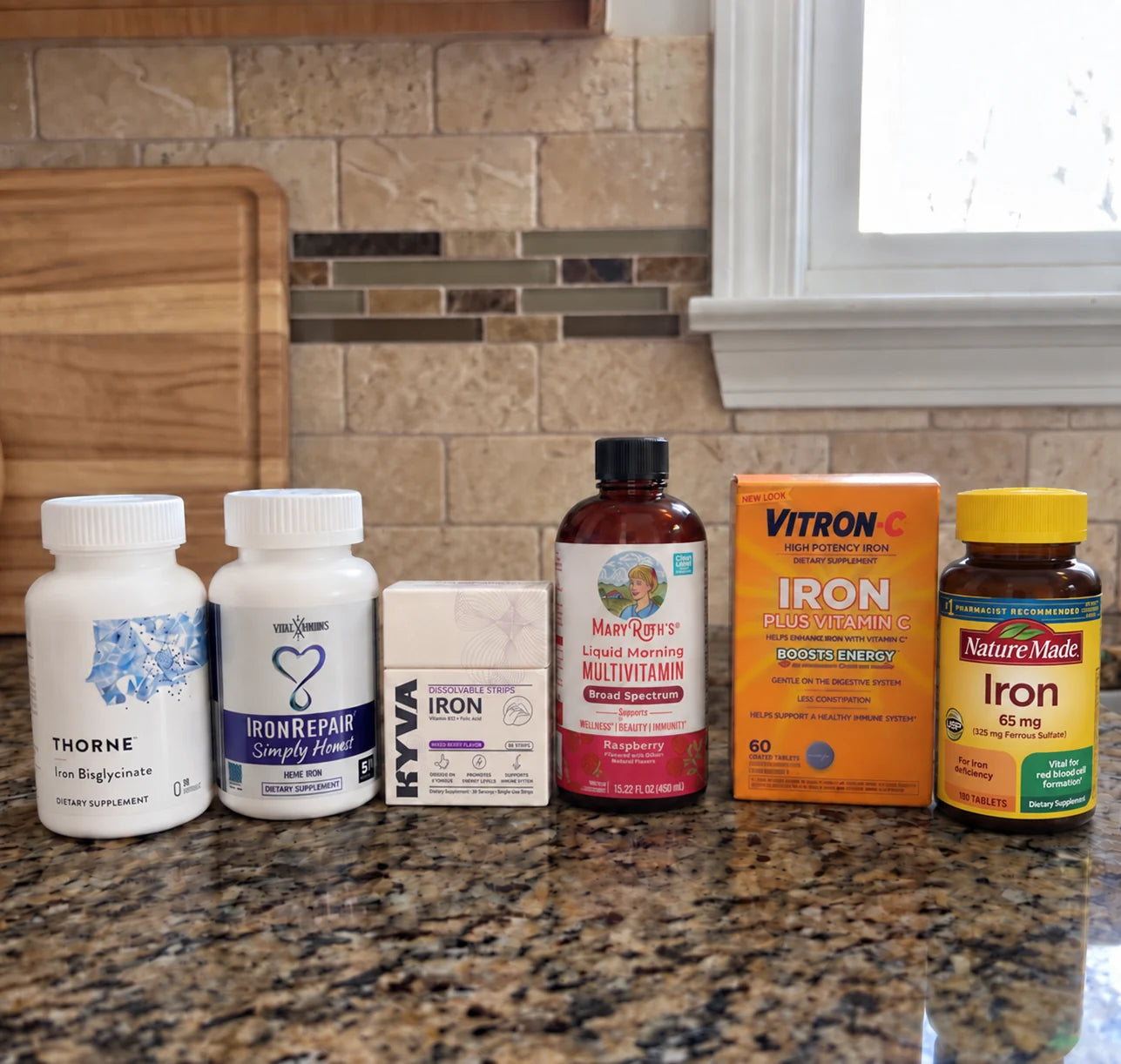 Supplement packages, including KYVA Iron Strips, arranged on a kitchen counter